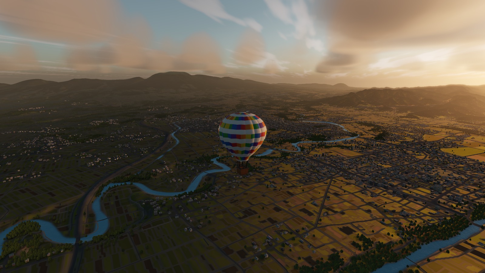A hot air balloon drifting low over a river valley of rice fields at sunrise