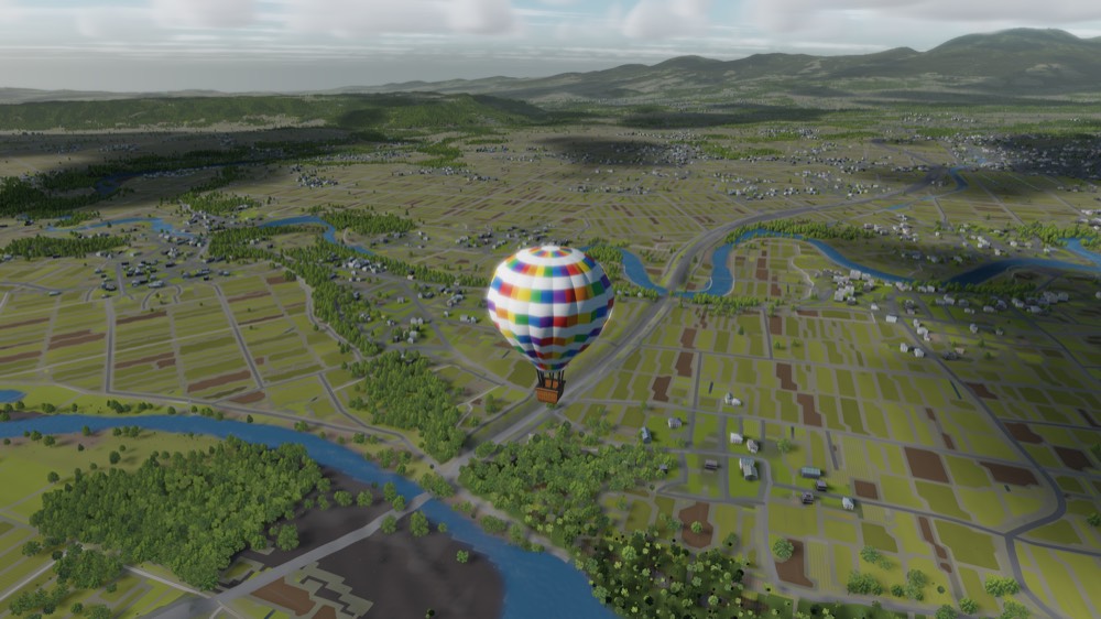 A balloon low over a patchwork of fields, rivers and roads