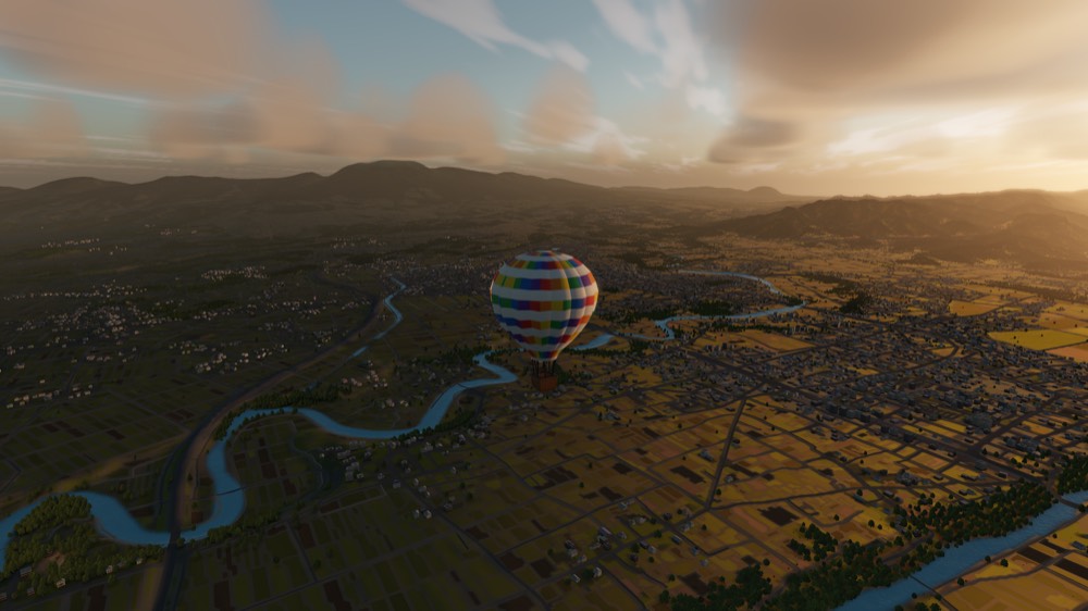 A balloon over a river valley of rice fields as the sun comes up