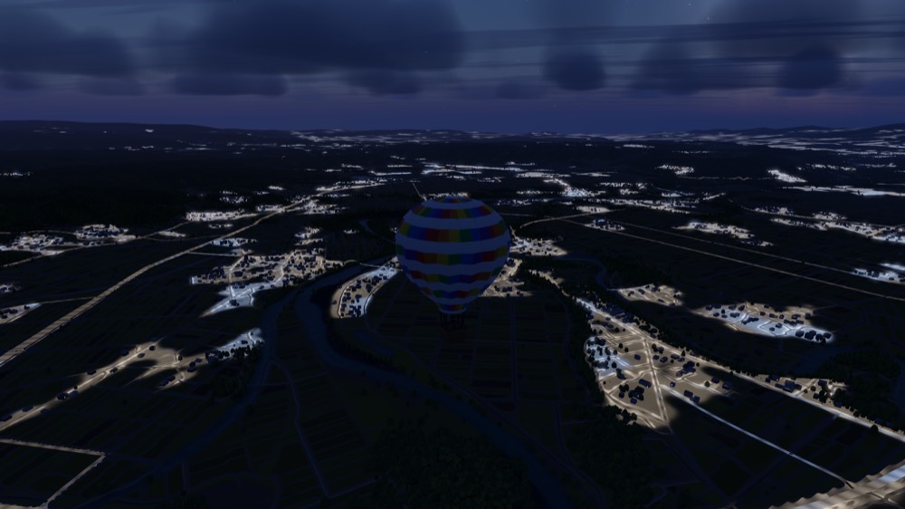 A balloon over a town as its lights come on at dusk