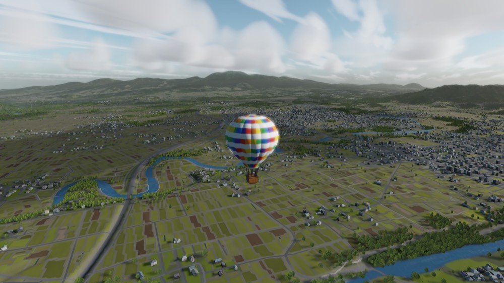 A balloon above green fields and a town under a clear morning sky