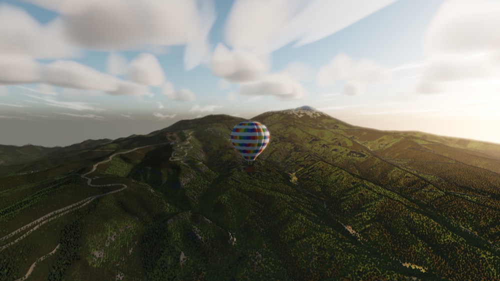 A balloon crossing a forested ridge with a distant snow-capped peak