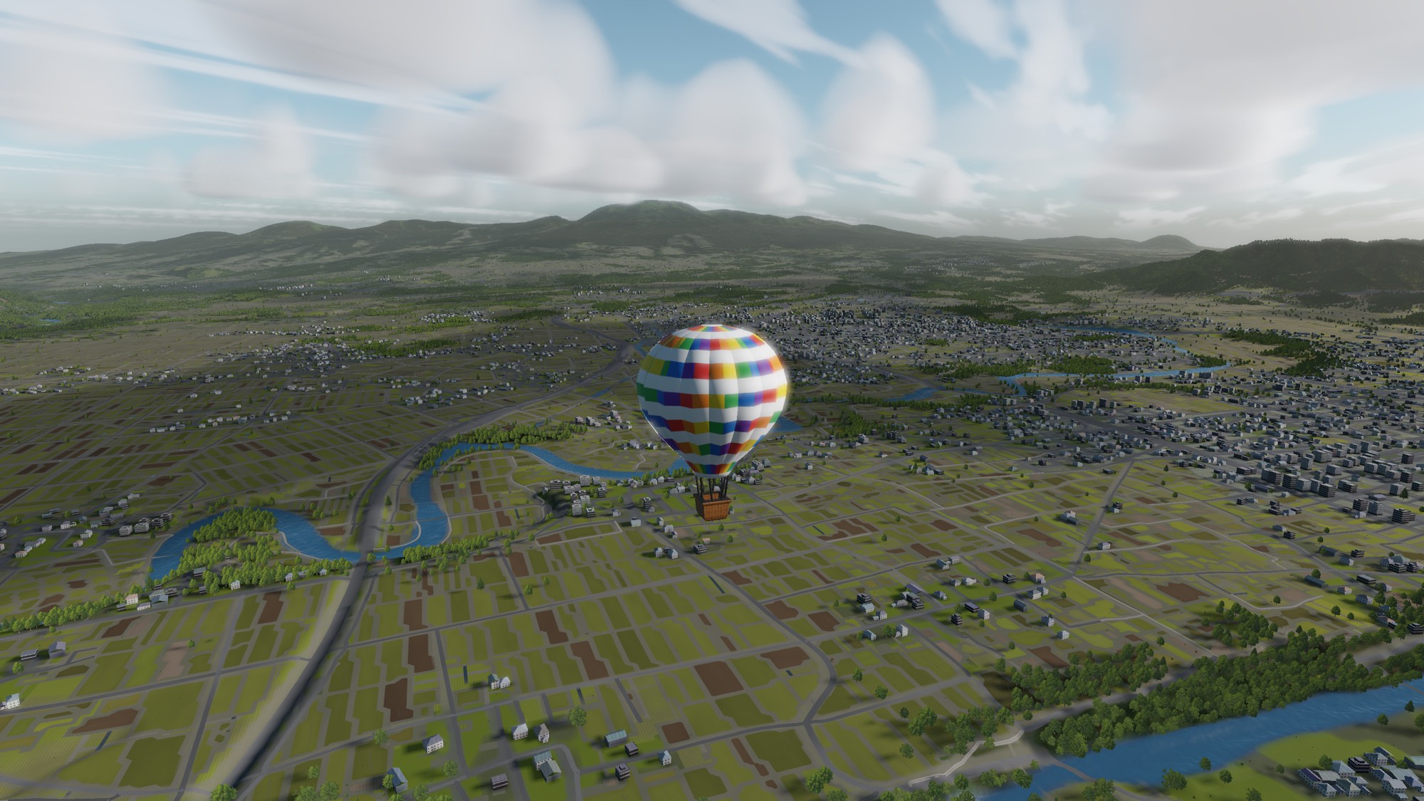 A balloon above green fields and a town under a clear morning sky