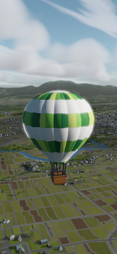 A green and white banded balloon low over a patchwork of fields