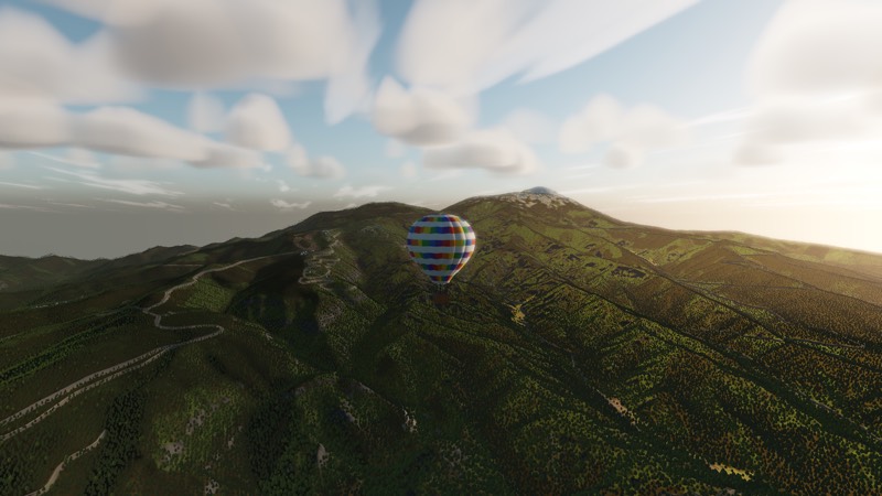 A balloon crossing a green ridge in golden light with a distant peak beyond